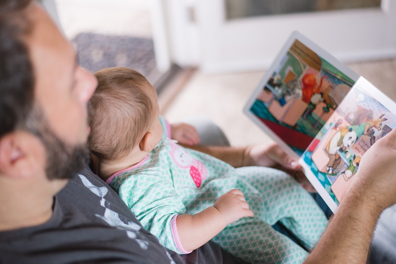 dad shows books to his baby